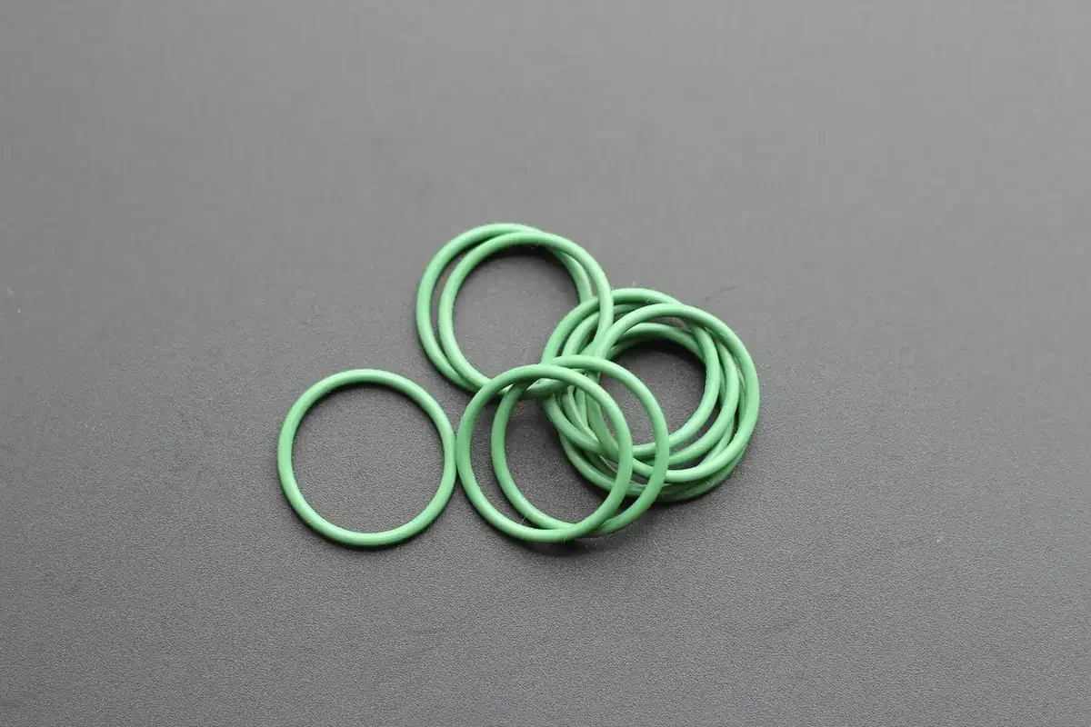 Grüne O-Ringe aus Perfluorelastomer auf grauem Studiohintergrund angeordnet
