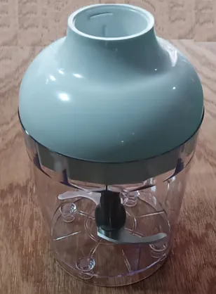 Mintgrüner Deckel auf einem transparenten Zerkleinerbecher mit zentraler Messernabe